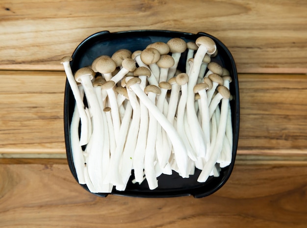 Funghi freschi affettati su un piatto quadrato isolato su sfondo di legno shabu hot pot ingredienti