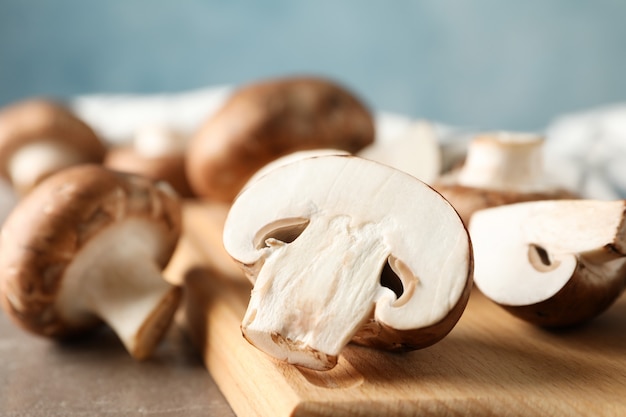 Funghi freschi del fungo prataiolo e bordo di legno su fondo grigio, fine su