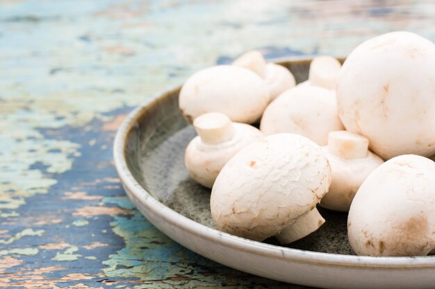 Funghi freschi in un piatto su una vecchia tavola di legno