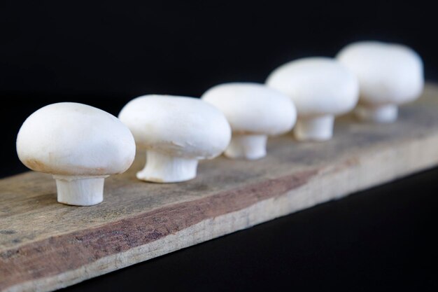 Funghi freschi sul tagliere di legno su sfondo nero