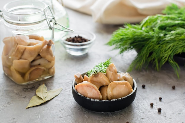 Funghi in salamoia - porcini in una ciotola e in un barattolo di vetro sul tavolo. Cibo vegetariano biologico.