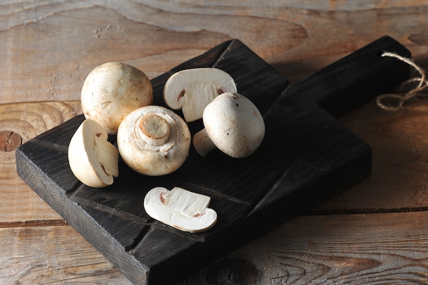 Funghi prataioli freschi dei funghi bianchi su di legno rustico