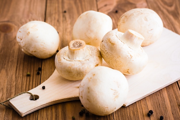 Funghi prataioli freschi interi sul tagliere sulla tavola di legno