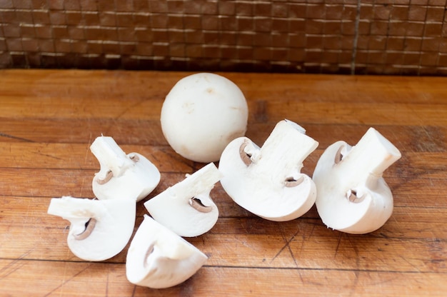 Funghi prataioli interi e tagliati su una tavola di legno