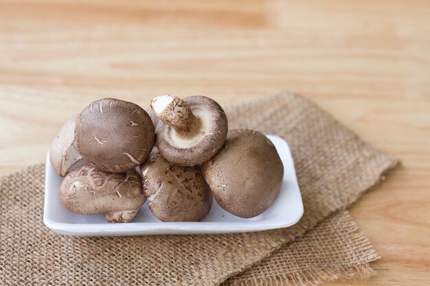 Fungo di shiitake sul piatto bianco sulla tavola di legno.