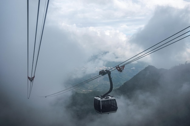 Funivia bianca che fa un giro turistico del villaggio di Sapa nella valle attraverso la nebbia