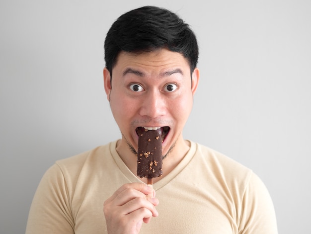 Funny face L&#39;uomo asiatico mangia il cioccolato al cioccolato e vaniglia.