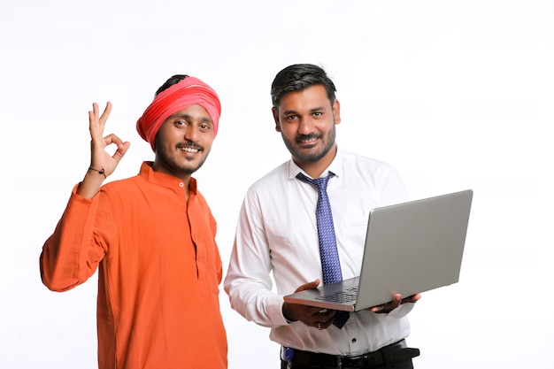 Funzionario di banca indiano o impiegato del governo aziendale che mostra alcune informazioni all'agricoltore nel computer portatile.
