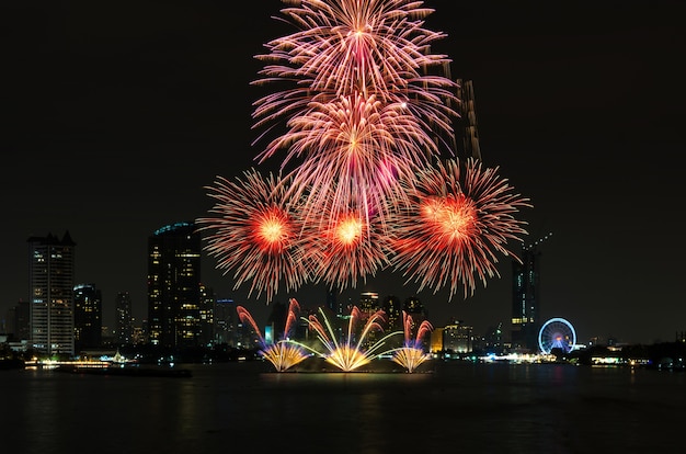Fuochi d&#39;artificio stupefacenti di celebrazione sopra il fiume con paesaggio urbano di Bangkok