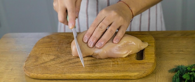 Fuoco selettivo della carne di pollo di decapaggio della donna