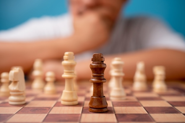 Fuoco selettivo di scacchi di re marrone e strategia di pensiero dell'uomo d'affari e valutazione del concorrente in concorrenza.