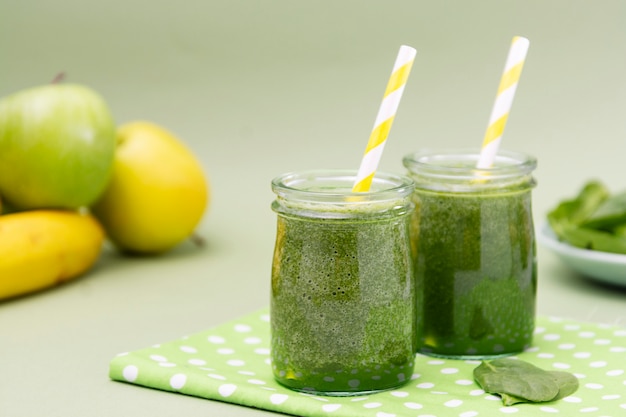 Fuoco selettivo di vetro mescolato del frullato verde, fondo verde. Cibo salutare.