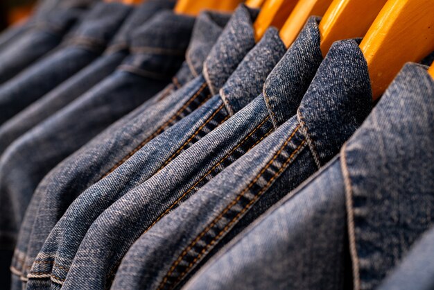 Fuoco selettivo sui jeans della giacca che appendono sulla cremagliera nel negozio di vestiti.