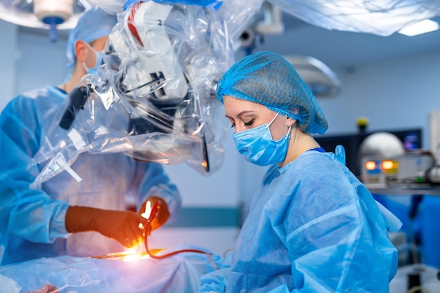 Fuoco selettivo sul processo di operazione di neurochirurgia. Assistente infermiera donna in sala operatoria. Interno moderno della clinica.