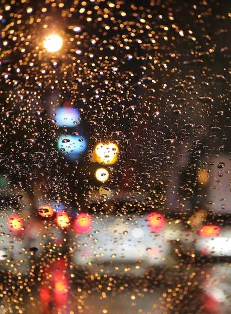 Fuori fuoco di ingorgo nella notte piovosa vista dal parabrezza dell&#39;auto con le gocce di pioggia