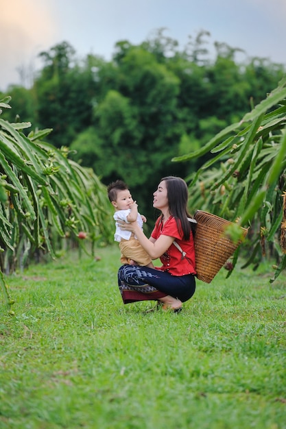 Fuori porta ritratto di giovane madre che indossa abiti tradizionali tailandesi nella fattoria naturale