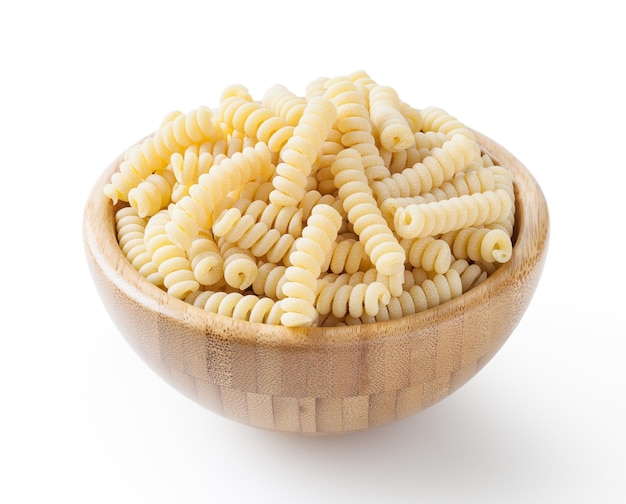 Fusilli corti bucati crudi in ciotola di legno isolata su sfondo bianco con tracciato di ritaglio