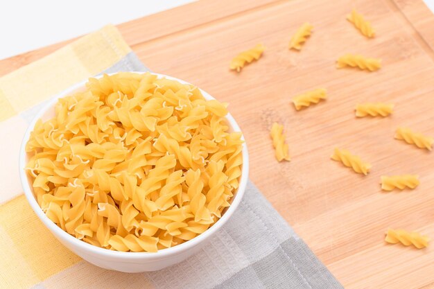 Fusilli crudi in ciotola bianca su tavola di legno