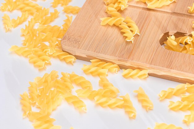 Fusilli crudi sparsi su tavola di legno