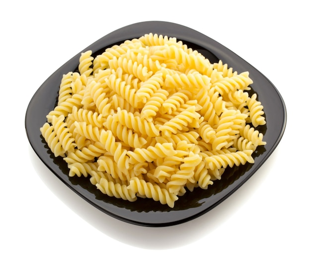 Fusilli della pasta nel piatto isolato su bianco