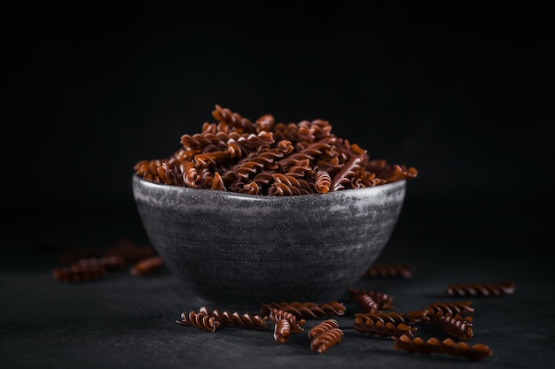 Fusilli di grano saraceno biologico crudo su sfondo scuro. Tagliatelle integrali senza glutine