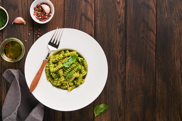 Fusilli italiani con pesto Fusilli con pesto di basilico ed erbe aromatiche parmigiano basilico e aglio su piatto bianco su sfondo vecchio tavolo in legno Vista dall'alto Spazio di copia Mock up