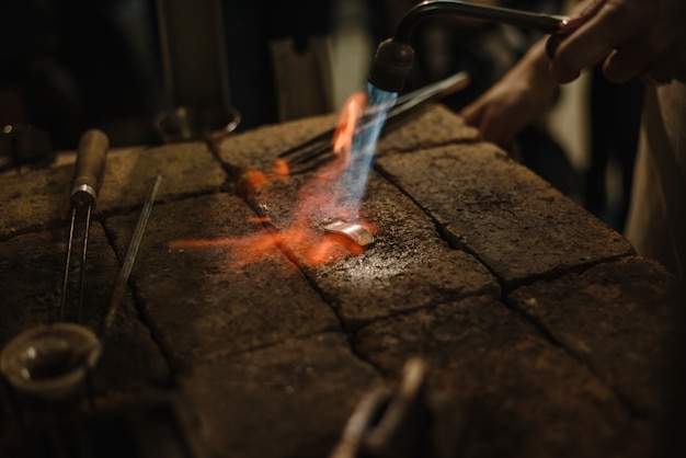 Fusione del metallo, gioielliere. il gioielliere versa l'anello. Cottura d'argento. Il lavoro del maestro in officina.