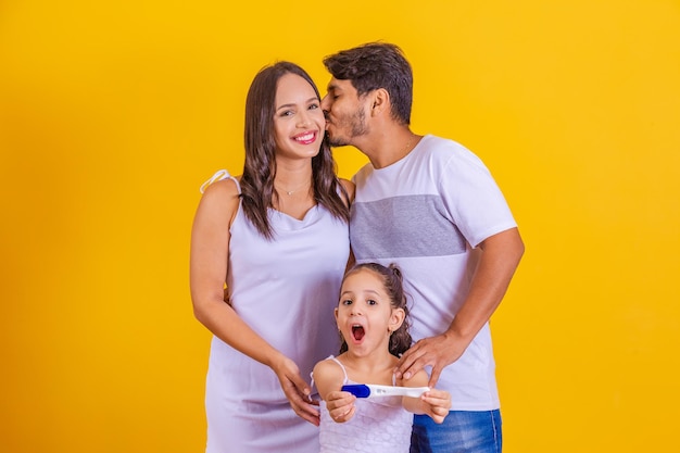 Futura sorella maggiore che tiene un test di gravidanza positivo con la sua famiglia in crescita Felice madre padre e figlia con test di gravidanza positivo