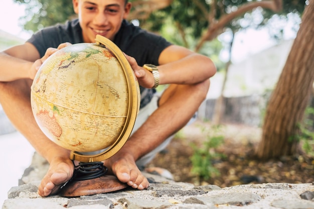 Futuro del mondo con un giovane adolescente caucasico che guarda un globo terrestre