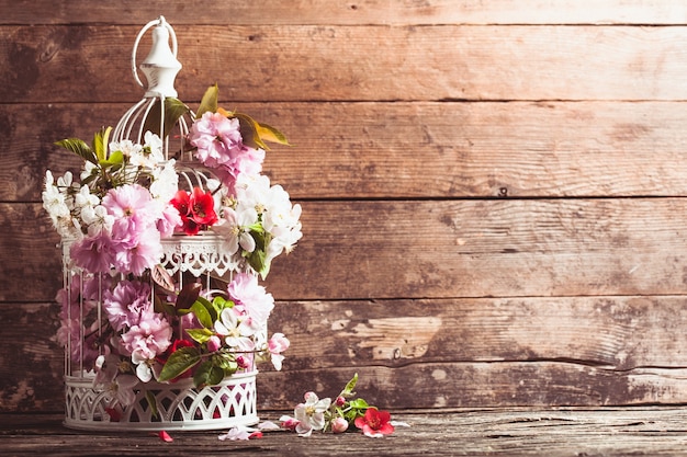 Gabbia per uccelli con fiori primaverili di sakura e fiori di frutta. Decorazioni per matrimoni con copia spazio