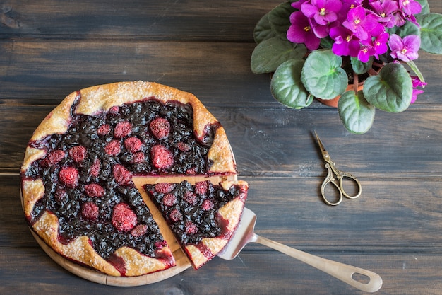 galette con frutti di bosco, fragola, mirtillo, mora. Fiore viola, forbici vintage.