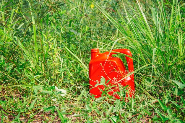 Gallone d'olio rosso con sfondo di foglia verde