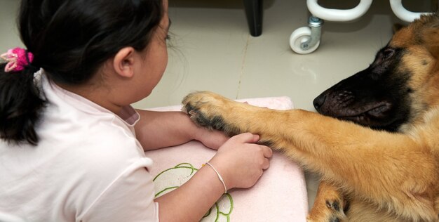 Gamba del cane della stretta del bambino sul pavimento