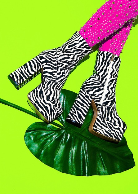 Gambe alla moda con stivali con stampa zebrata con tacco su verde minimal