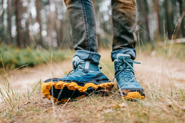 Gambe da uomo in scarponcini da trekking per attività all'aperto su strada forestale