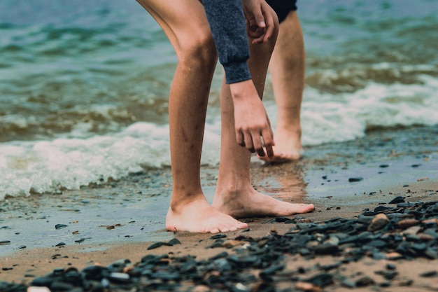 Gambe dei bambini di viaggio in spiaggia che camminano su una spiaggia di sabbia in riva al mare