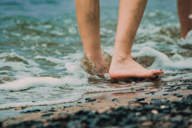 Gambe dei bambini di viaggio in spiaggia che camminano su una spiaggia di sabbia in riva al mare