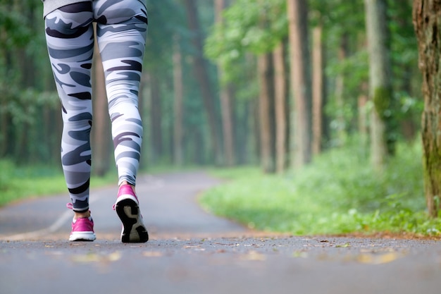 Gambe del corridore femminile di giovane forma fisica pronte per l'esecuzione sulla traccia della foresta