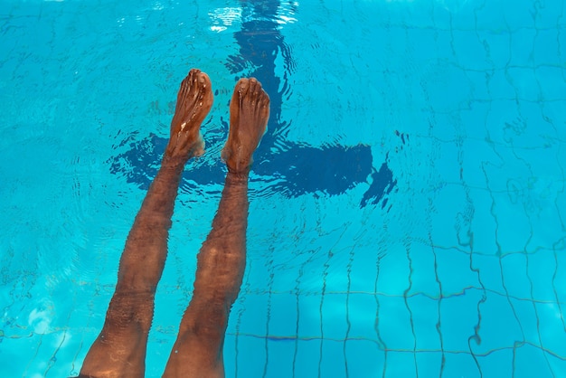 gambe dell'uomo afroamericano adulto sott'acqua in piscina swimming