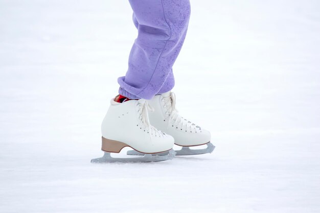 Gambe della donna di pattinaggio su ghiaccio sulla pista di pattinaggio sul ghiaccio. hobby e sport invernali