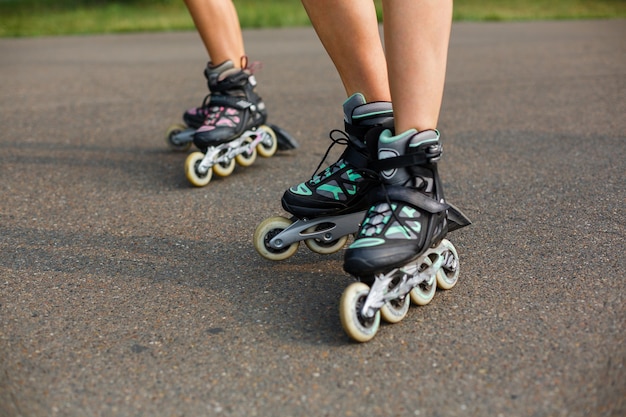 Gambe della giovane donna di sport sulla passeggiata del pattino a rotelle