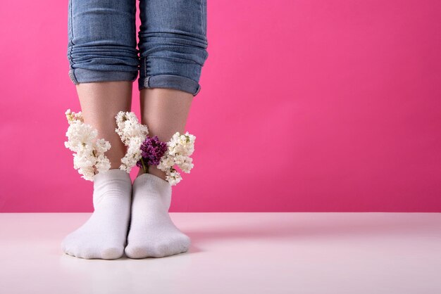 Gambe della ragazza in calzini in cui sono inseriti fiori lilla concetto di vene e gambe di salute femminile