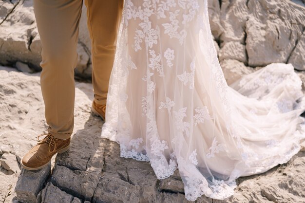 Gambe della sposa e dello sposo in piedi sul primo piano della roccia