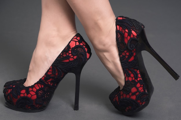 Gambe delle donne in scarpe di pizzo rosso con tacchi alti neri isolati