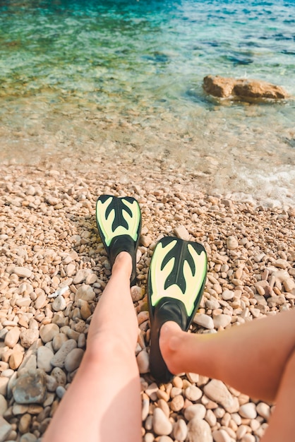 Gambe di donna in pinne in spiaggia mare sullo sfondo