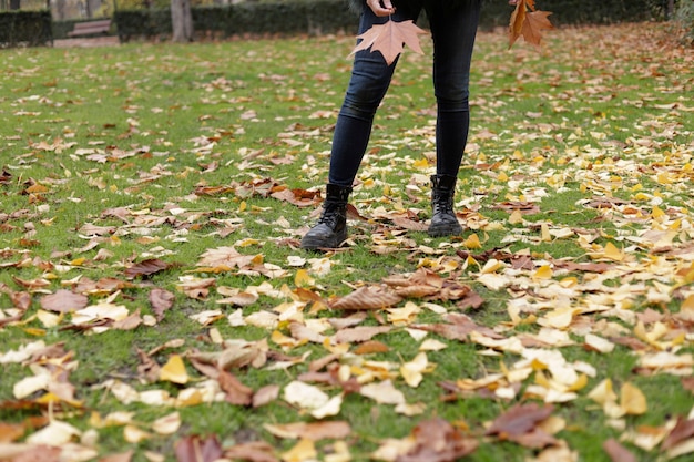 Gambe di donna nel parco con foglie d'autunno