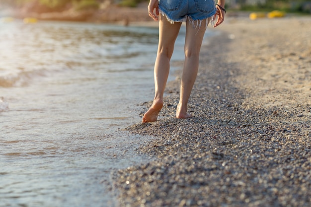 Gambe di donne che camminano sulla spiaggia al tramonto