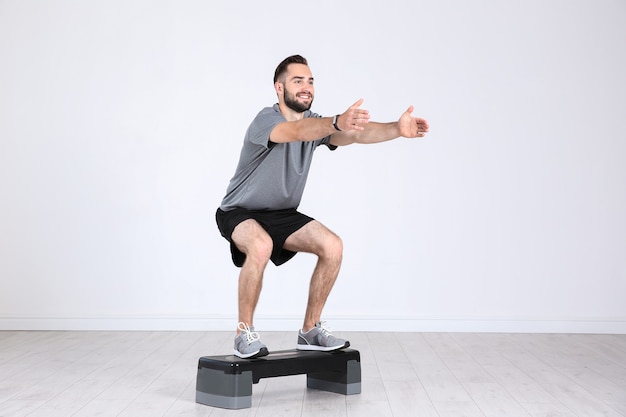 Gambe di formazione giovane uomo sportivo con stepper in palestra