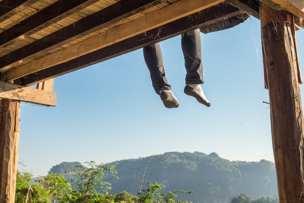 Gambe di seduta turistiche dell&#39;uomo che appendono sul terrazzo