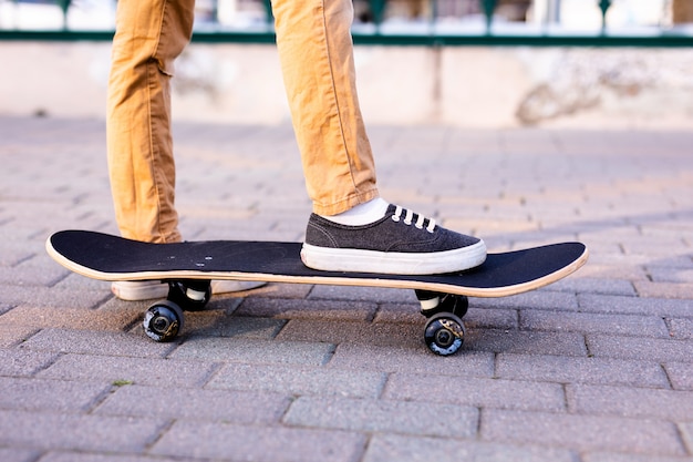 Gambe di skateboarder cavalcando skateboard sulla strada della città